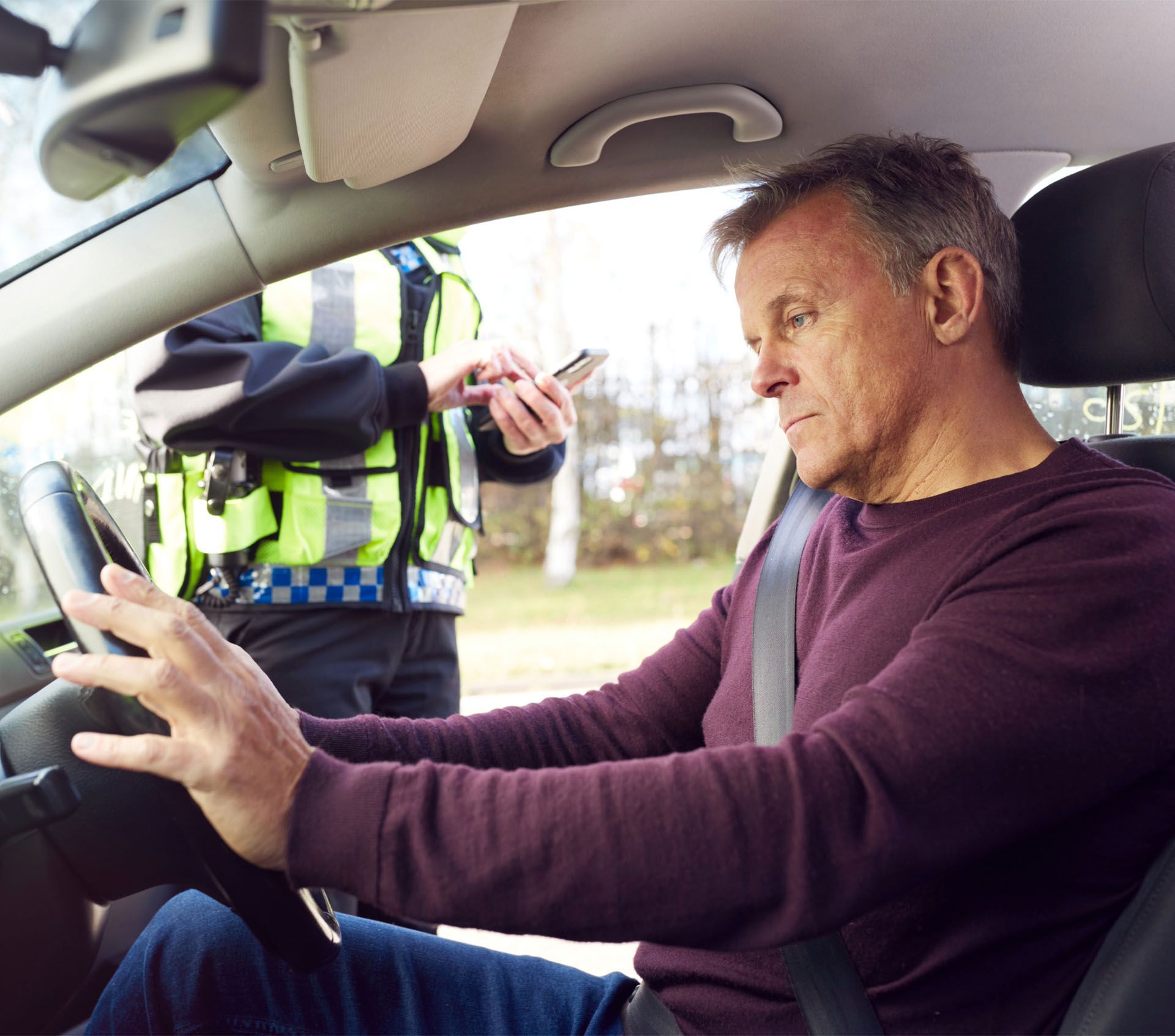 A man is sitting in a car talking to a police officer