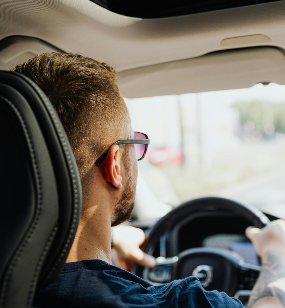 Father and child embrace in a car. The father smiles, wearing a striped shirt.