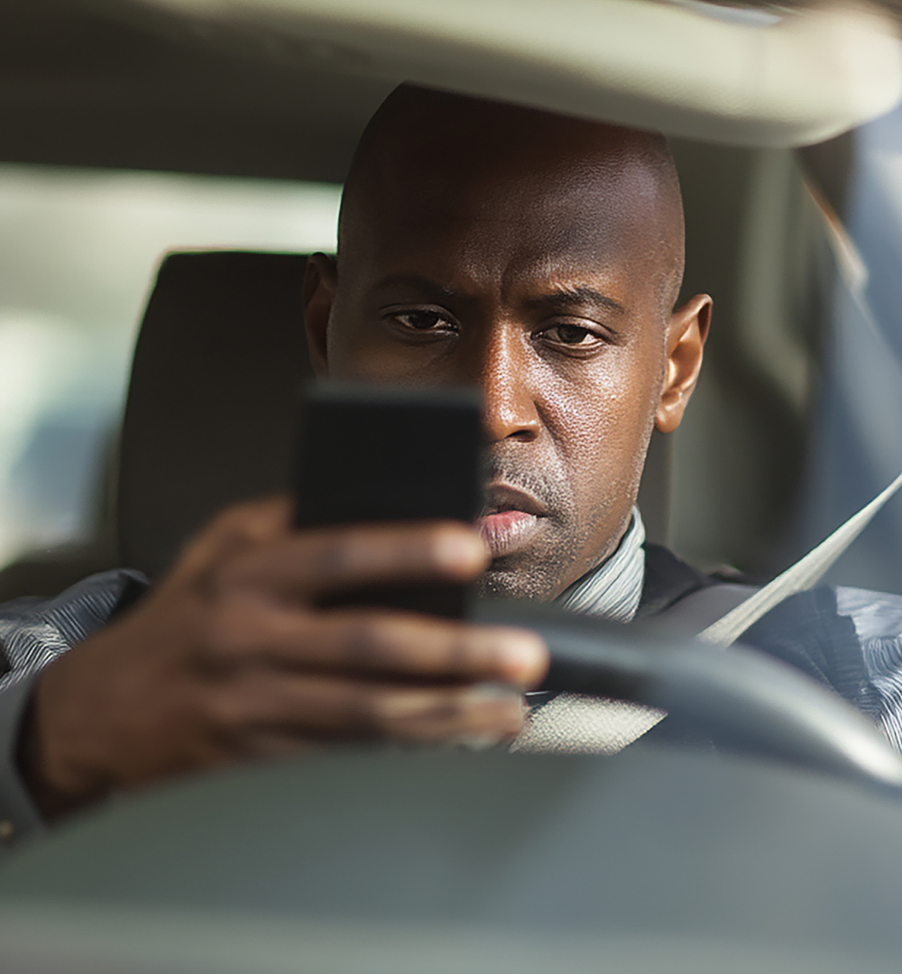 Father and child embrace in a car. The father smiles, wearing a striped shirt.