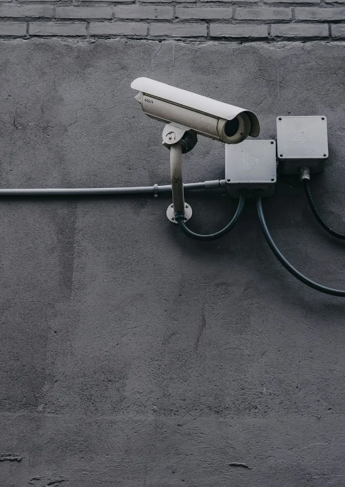 Security camera mounted on a gray wall, monitoring.