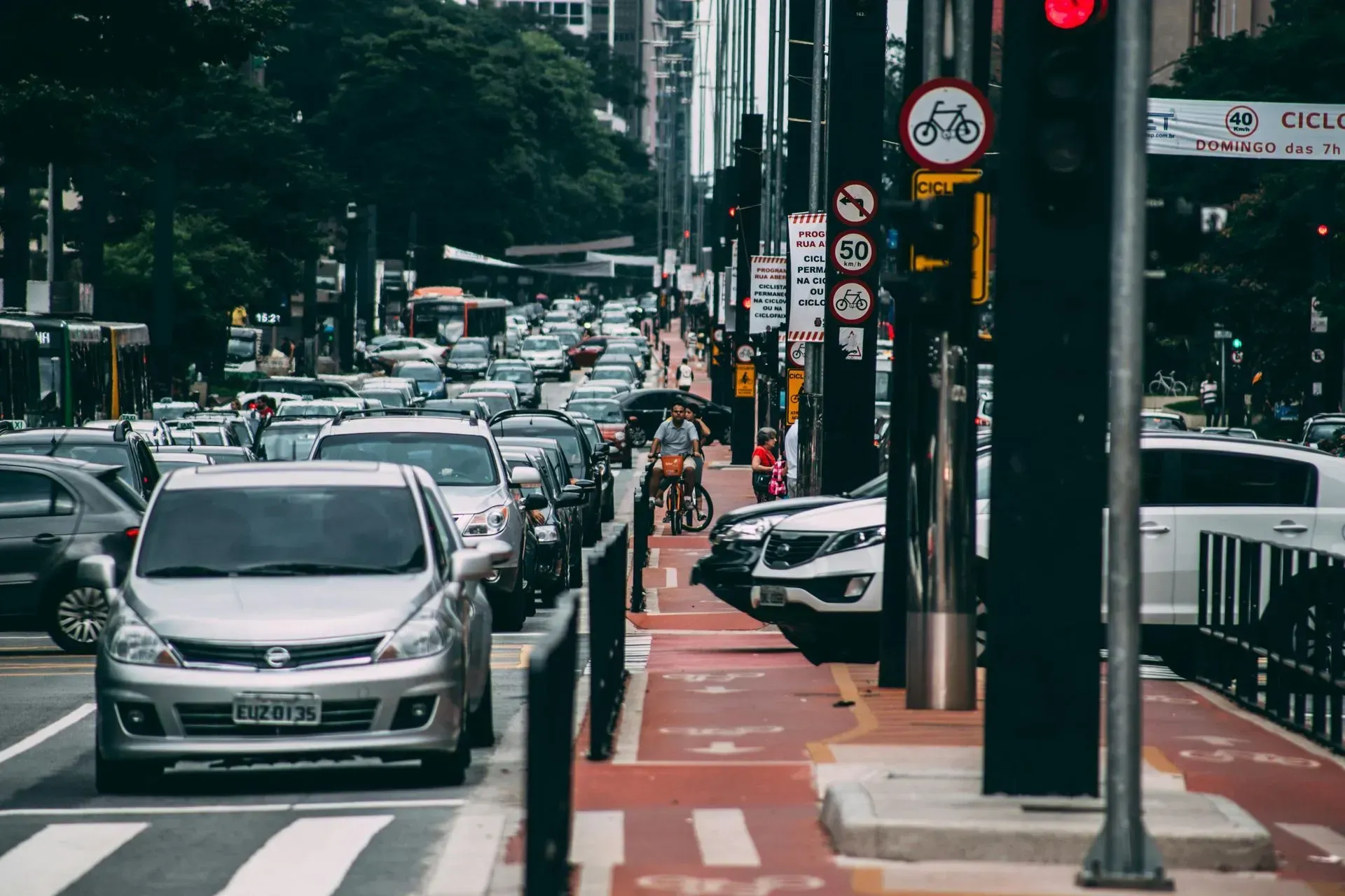 Busy city street scene with cars, a bicyclist, and traffic lights.