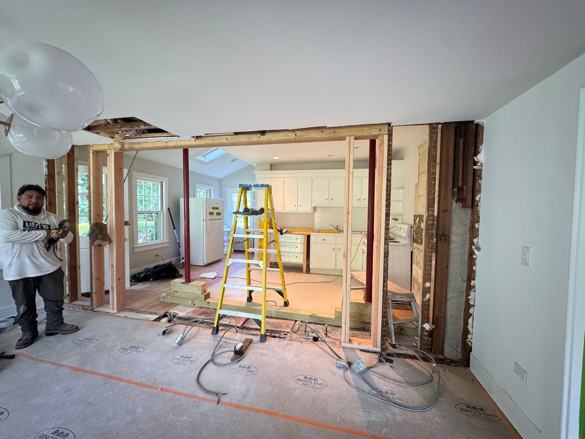 A rectangular wooden table on a white sheet in a garage, with a sander on it and tools below.