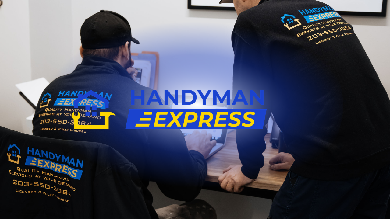 Three Handyman Express workers in black shirts sit around a table reviewing paperwork with a tablet.