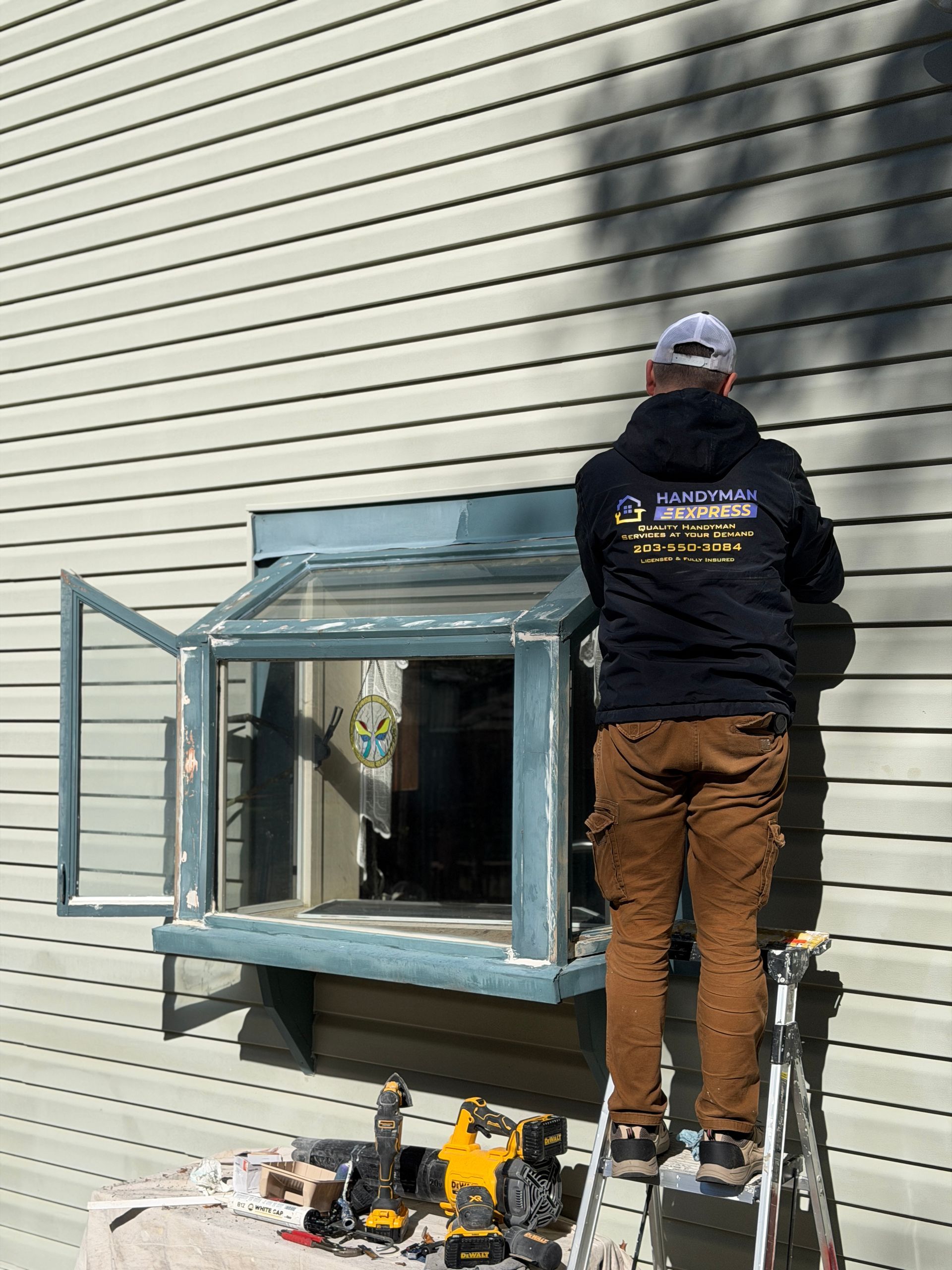 A rectangular wooden table on a white sheet in a garage, with a sander on it and tools below.