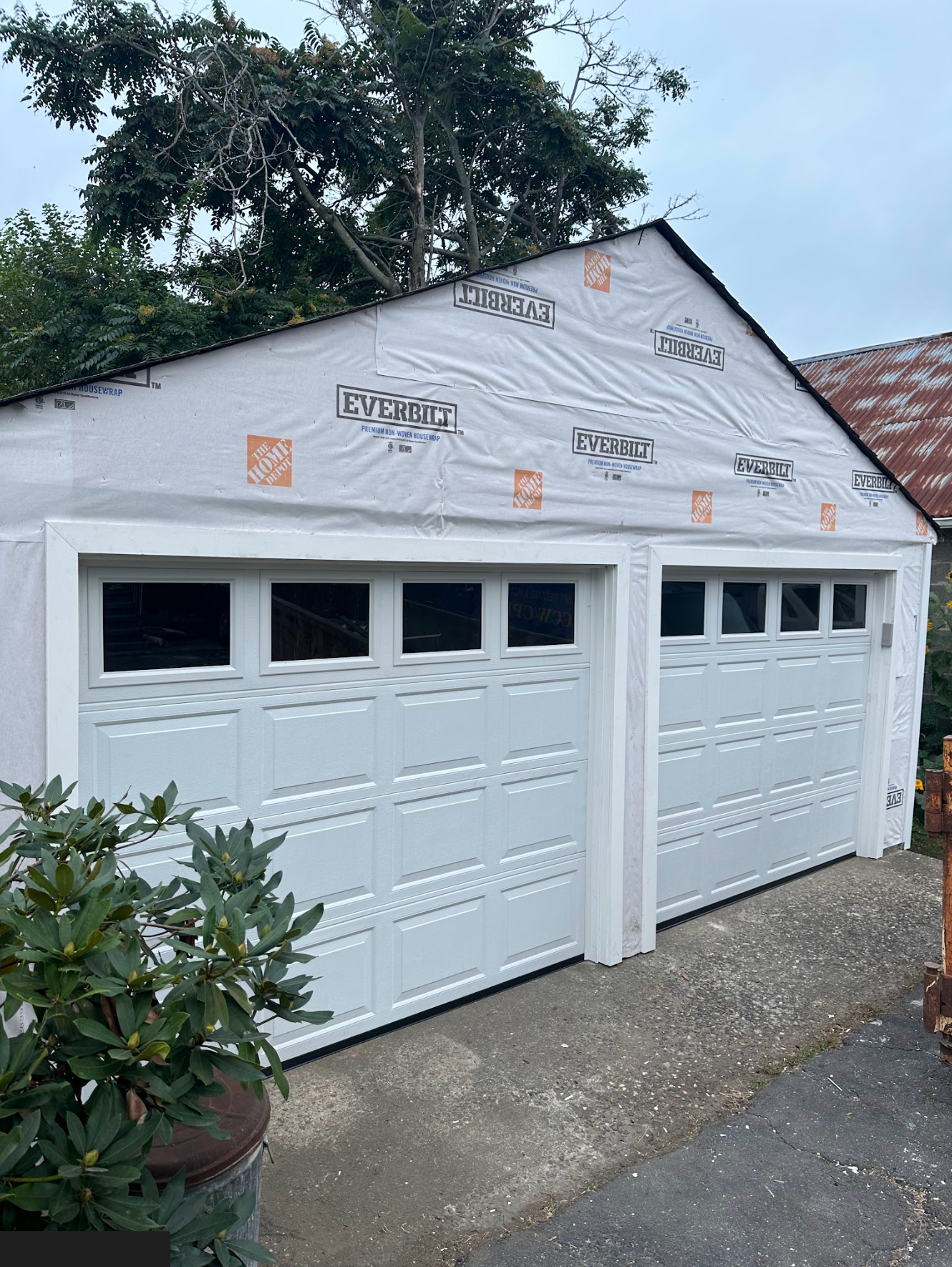 A rectangular wooden table on a white sheet in a garage, with a sander on it and tools below.