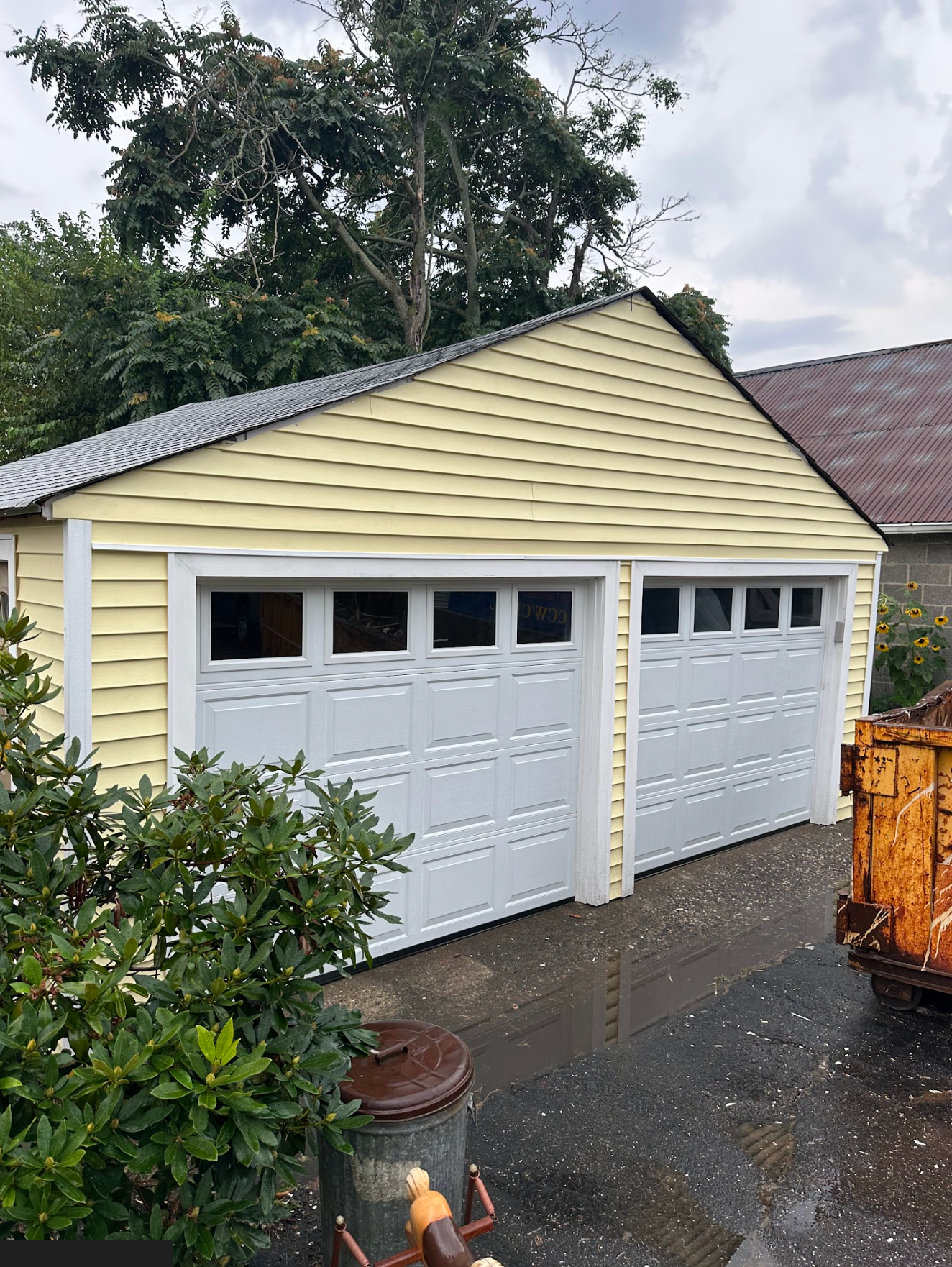 Long rectangular table, painted light gray, on a black metal base, in a garage. Paint supplies visible.