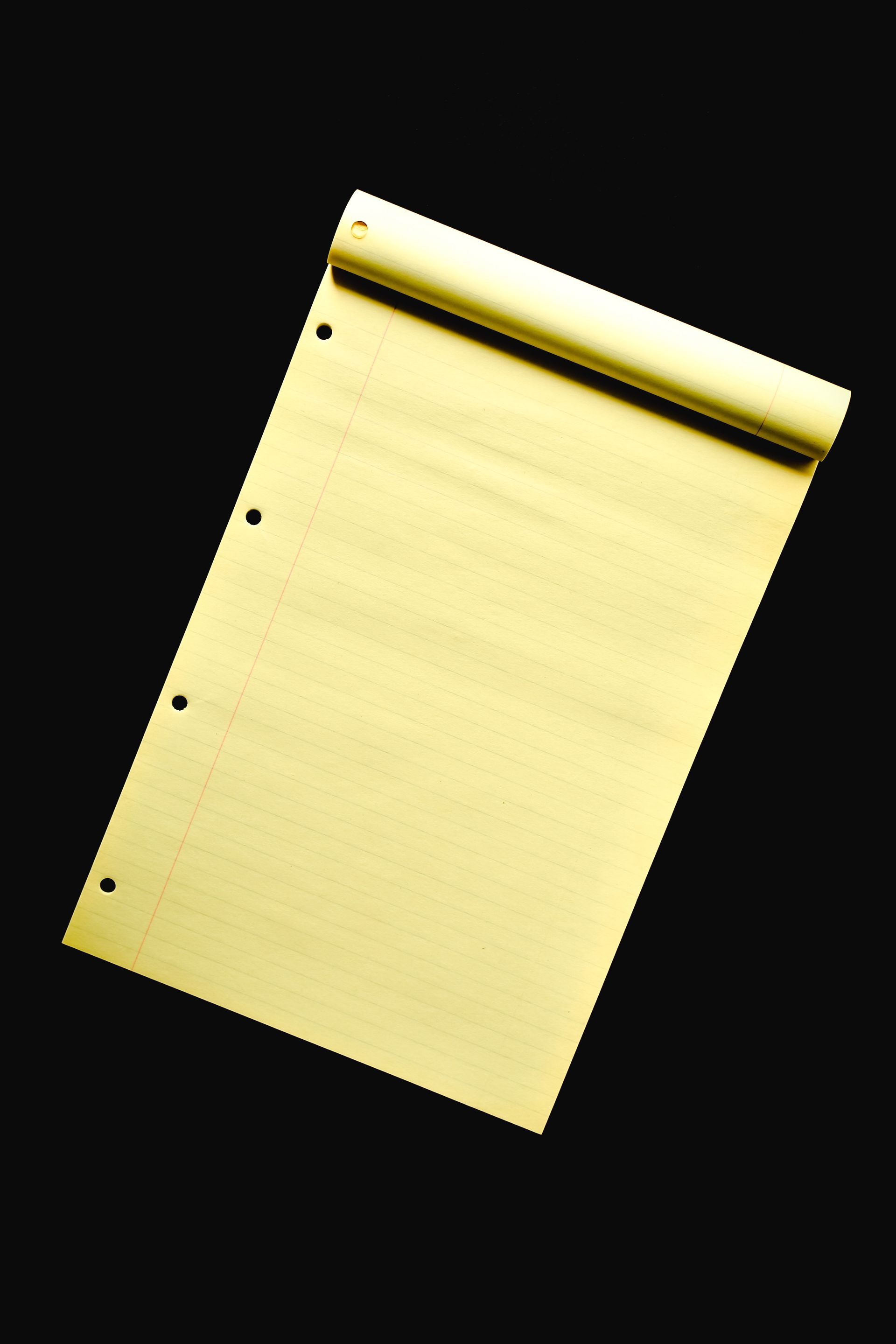 Yellow legal pad on a black background, slightly rotated.
