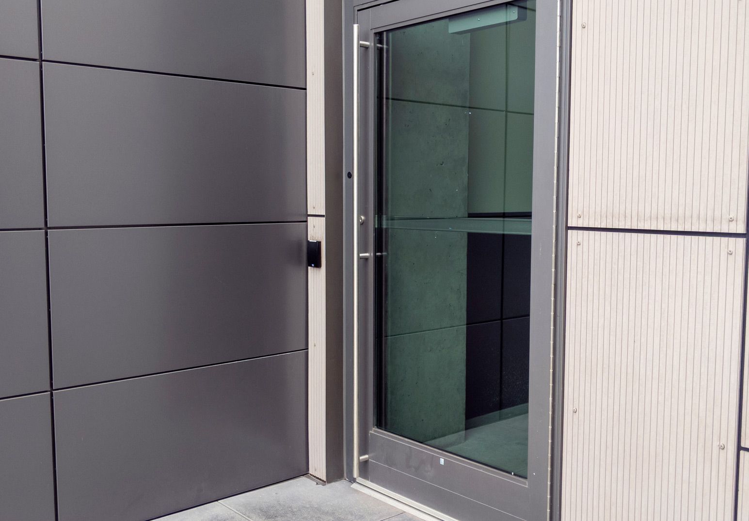 A door with a stainless steel handle is on the side of a building