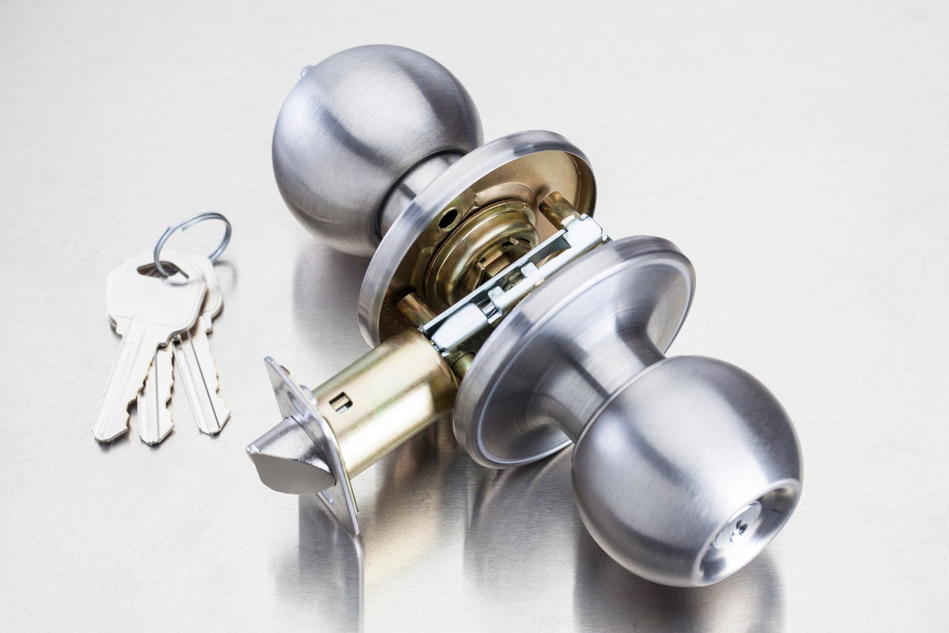 A stainless steel door knob with two keys next to it