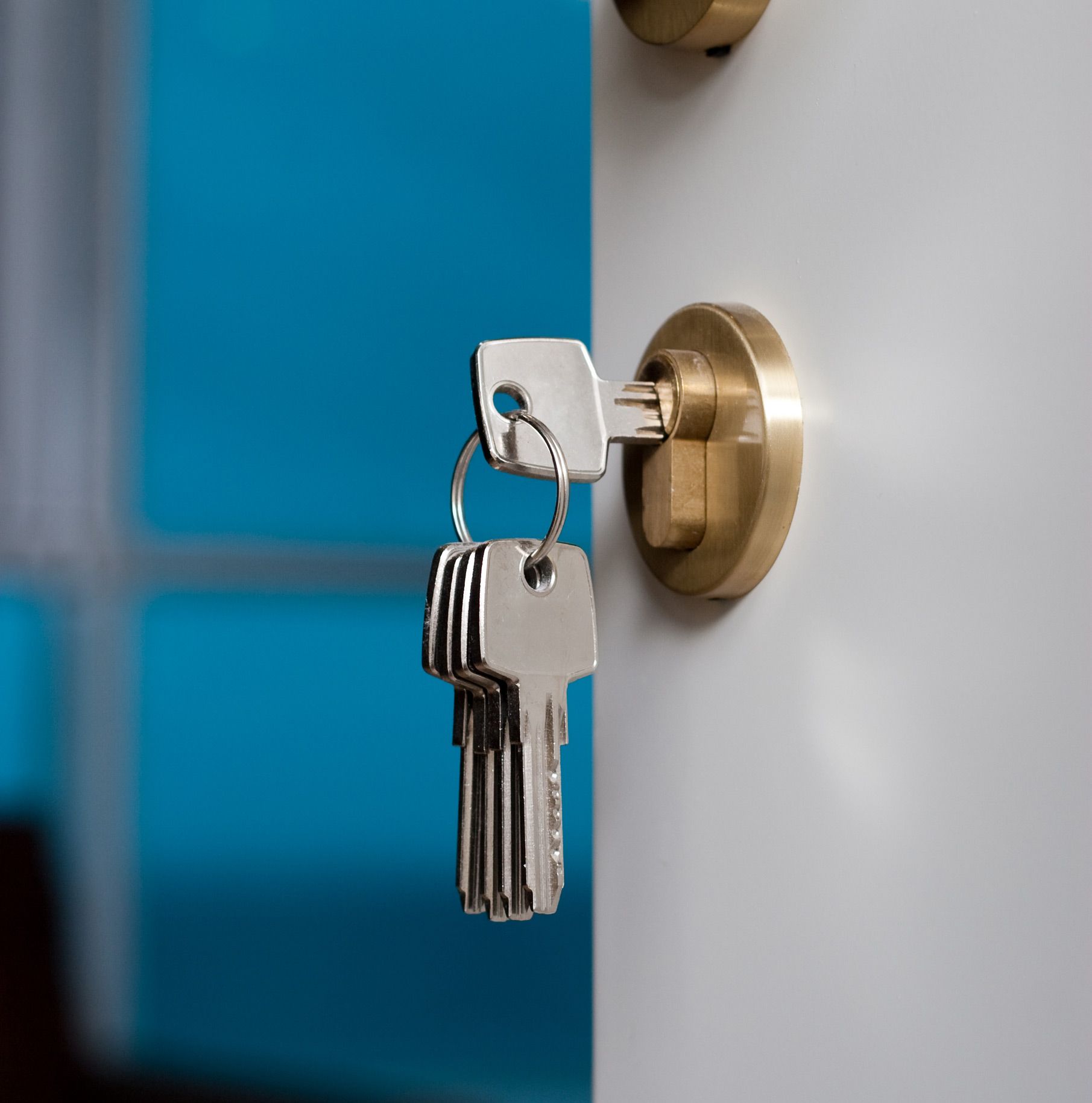 A bunch of keys are hanging from a keyhole on a door.