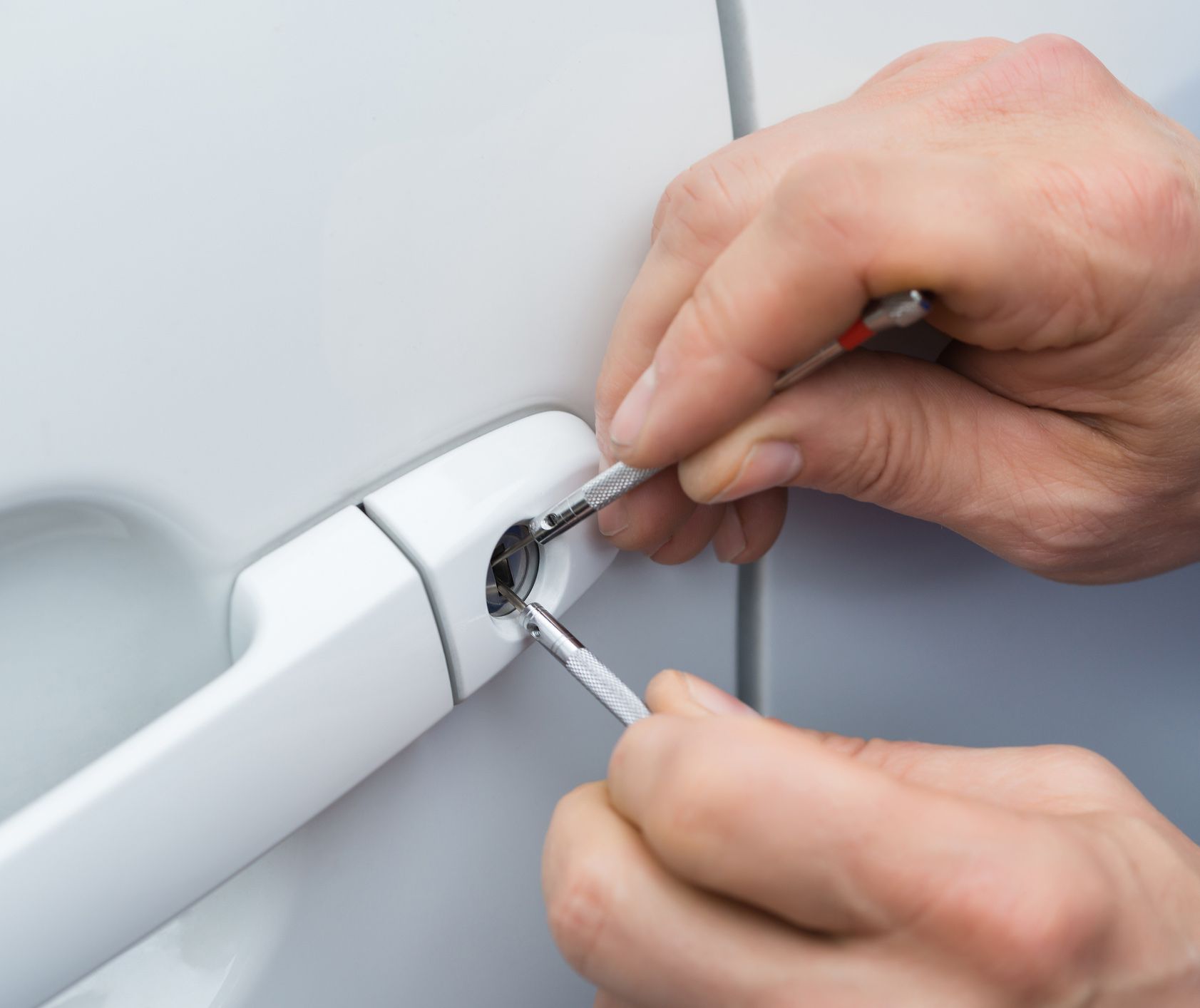 A person is opening a car door with a screwdriver