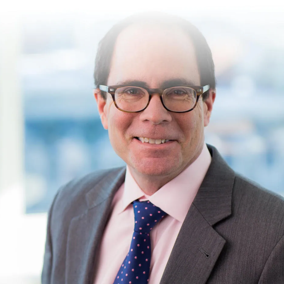 Man in suit, glasses, smiling; formal business portrait.