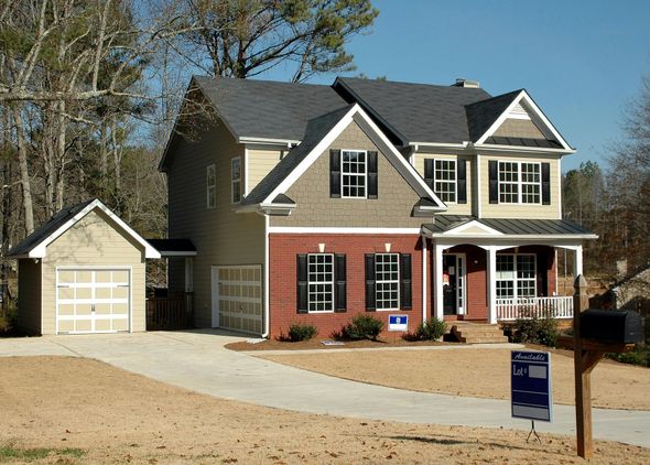Two-story house with attached garage, red brick and tan siding, gray roof, and a porch.