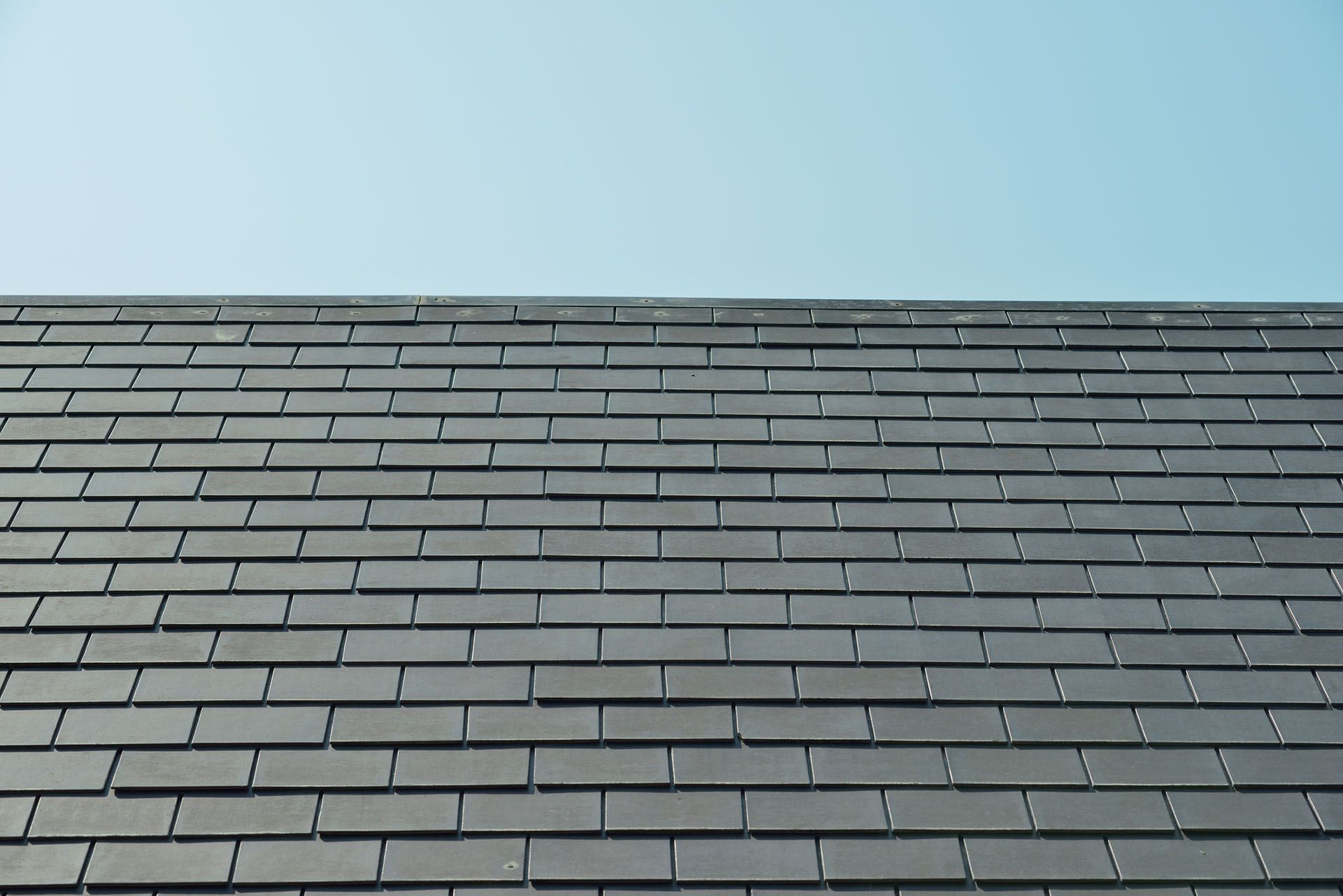 Close-up of a gray slate roof against a pale blue sky