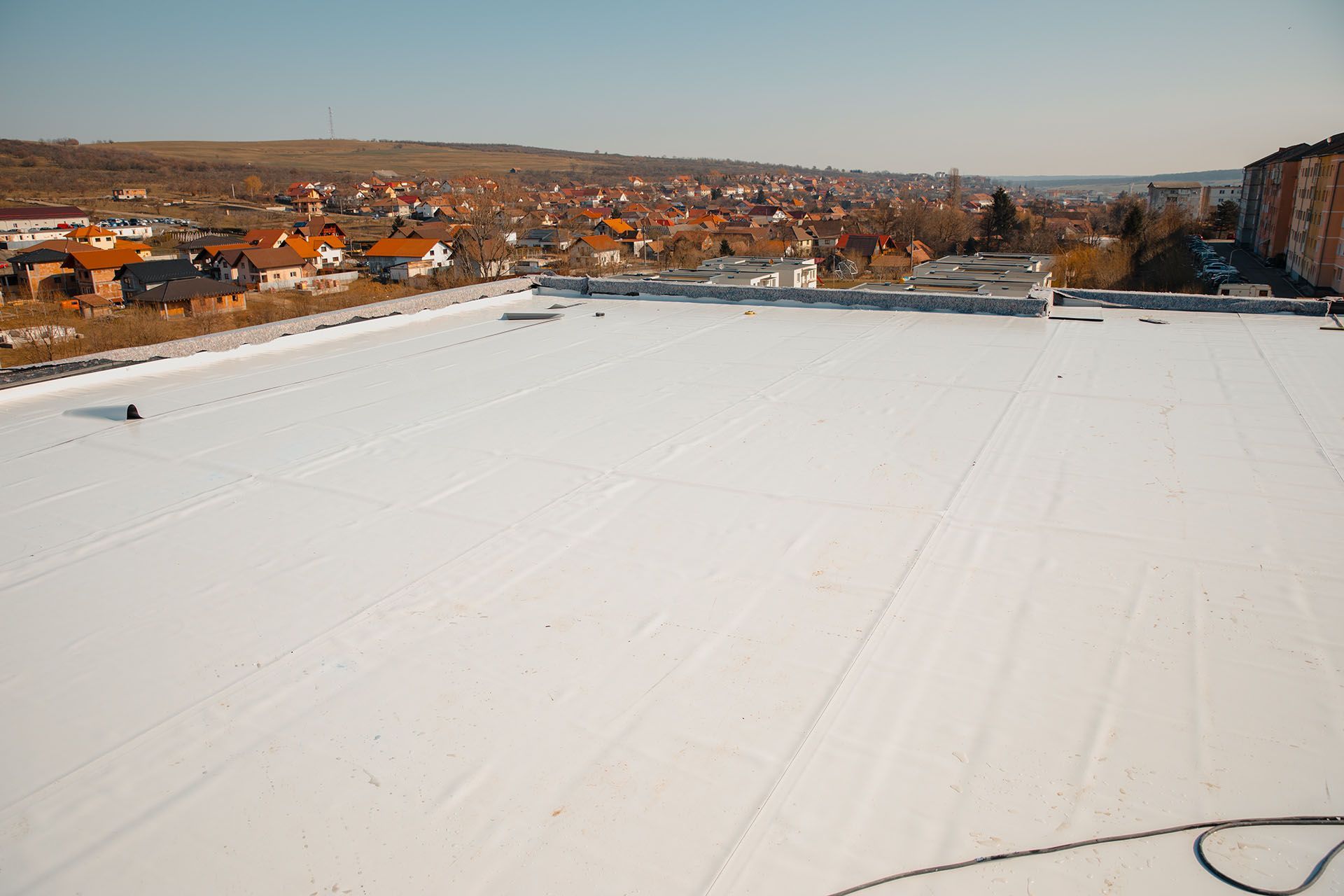 Flat white roof with residential buildings in the background
