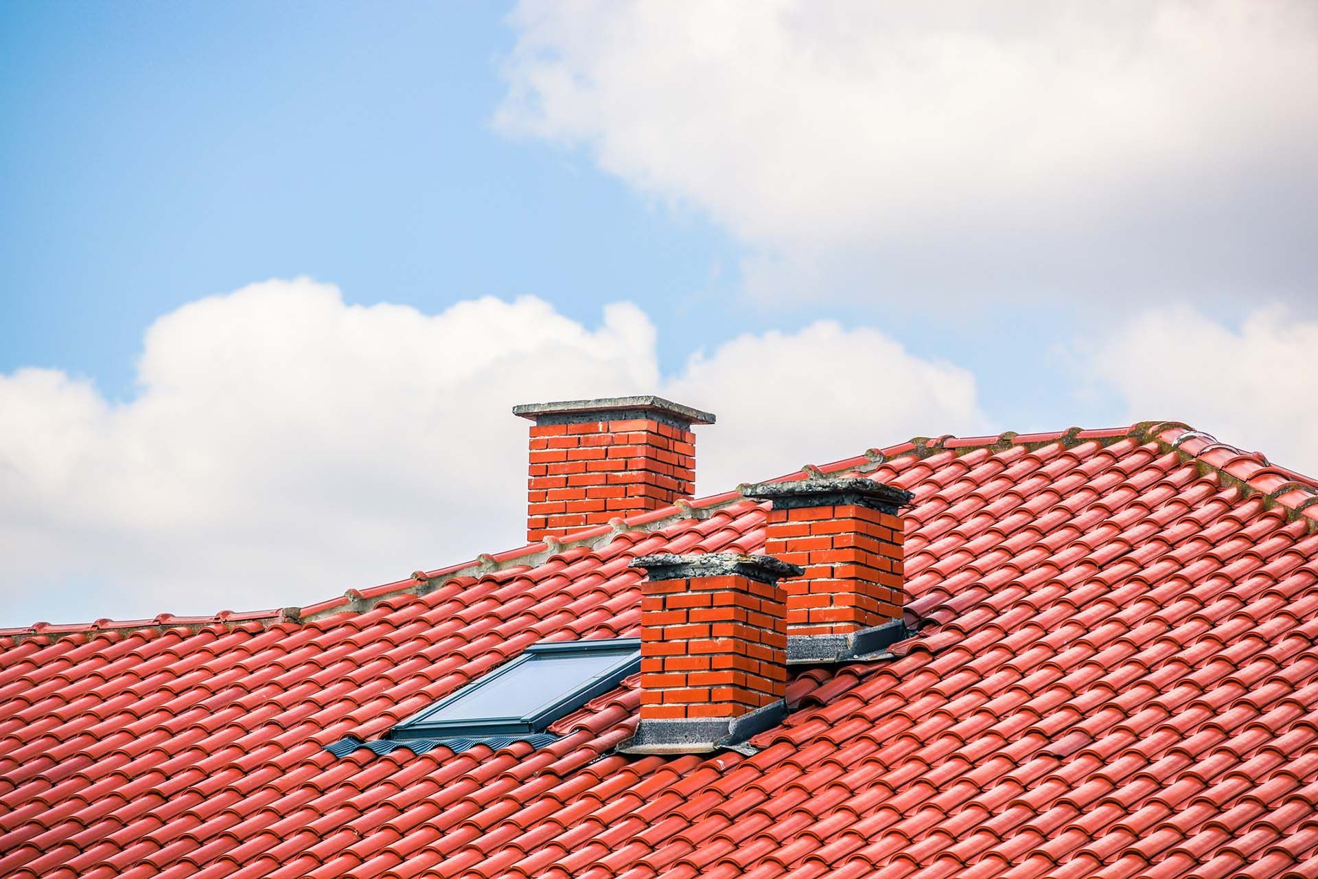 Red tiled roof with brick chimneys and a skylight