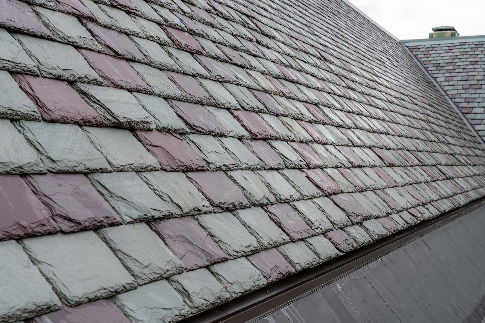 Close-up of a roof with a pattern of gray and reddish-purple slate tiles