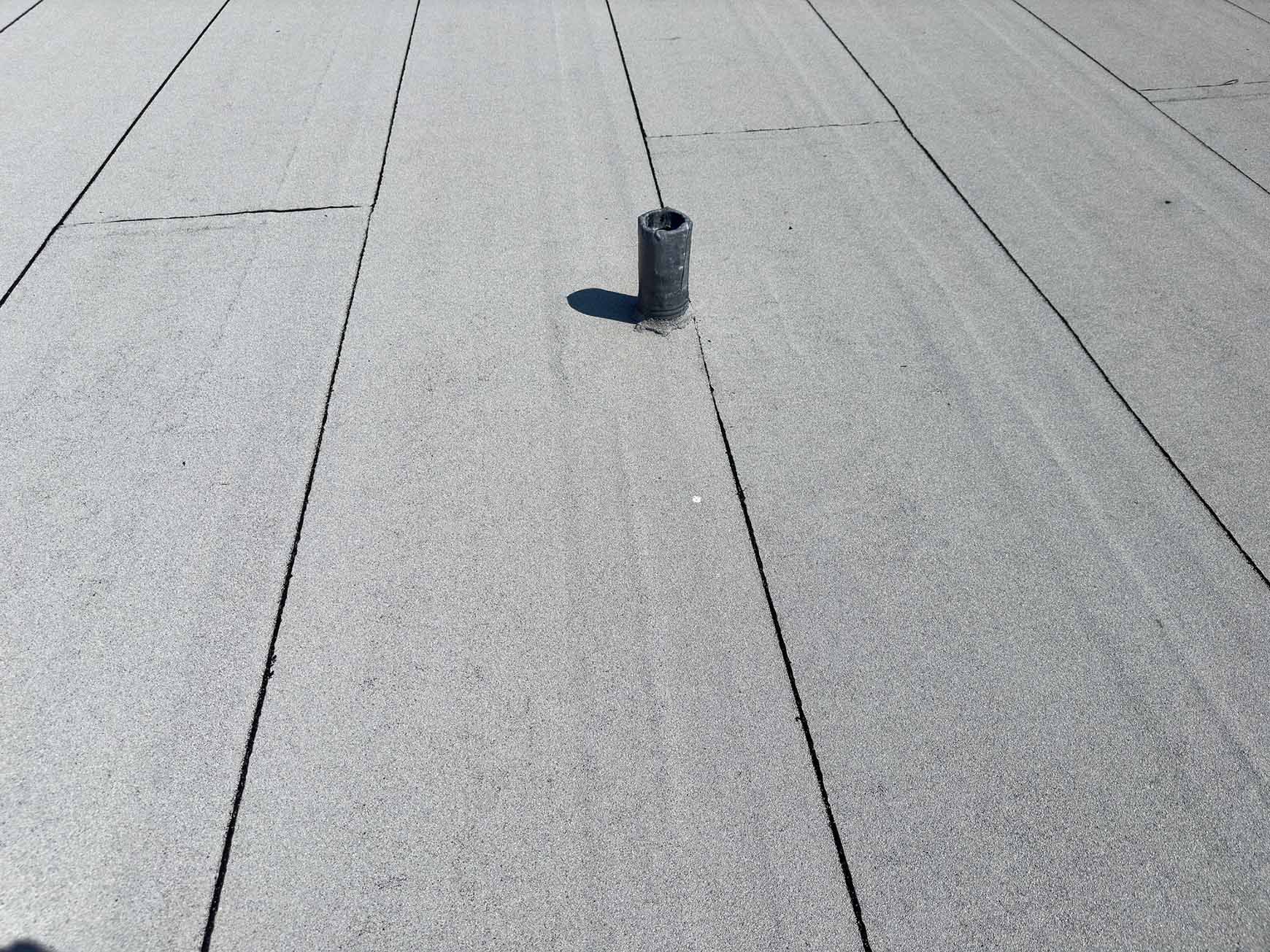 Gray flat roof with a black pipe