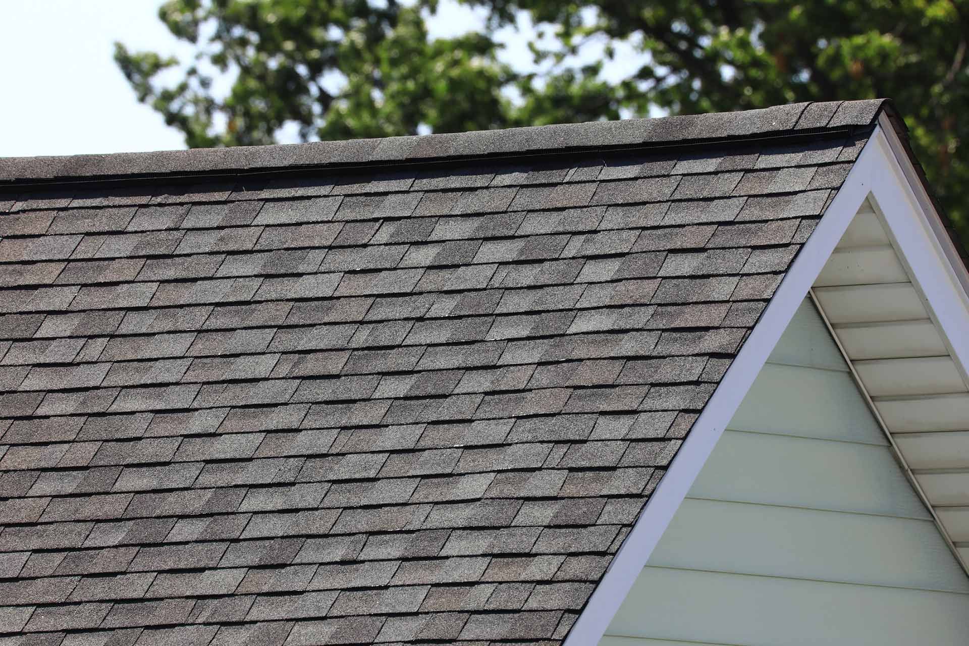 Close-up of a roof with gray shingles and white trim