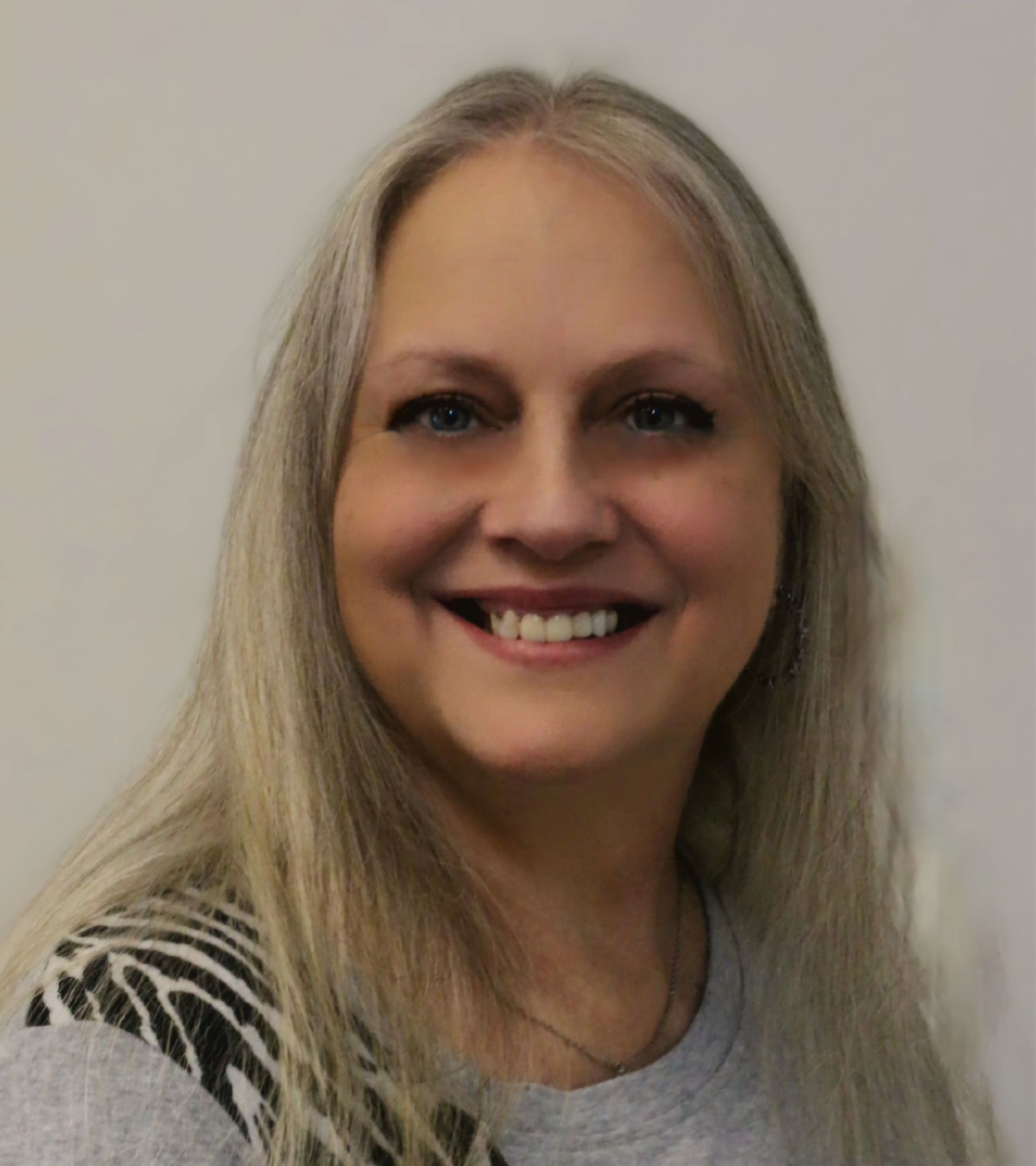 A woman with long hair is smiling and wearing a green shirt.