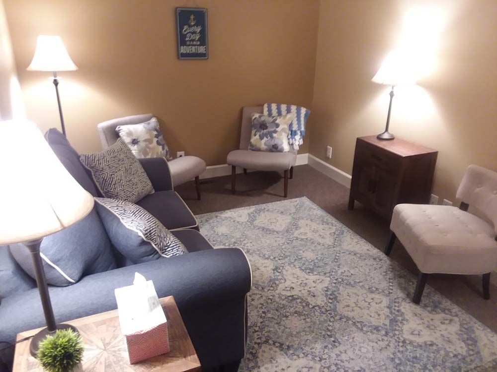A living room with a blue couch and white chairs