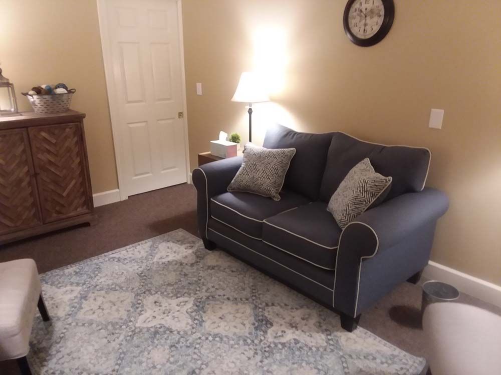 A living room with a blue couch and a clock on the wall.