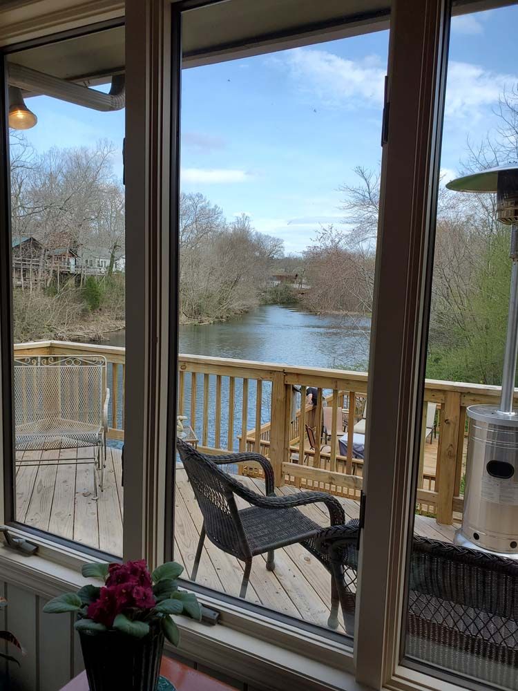 A view of a deck with chairs and a heater from a window.