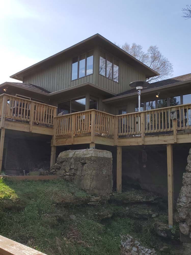 A large house with a large wooden deck on top of it.