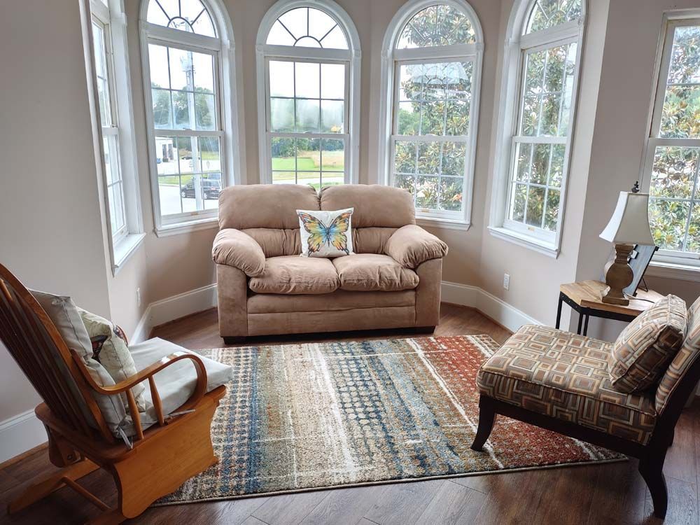 A living room with a couch , chairs , and a rug.