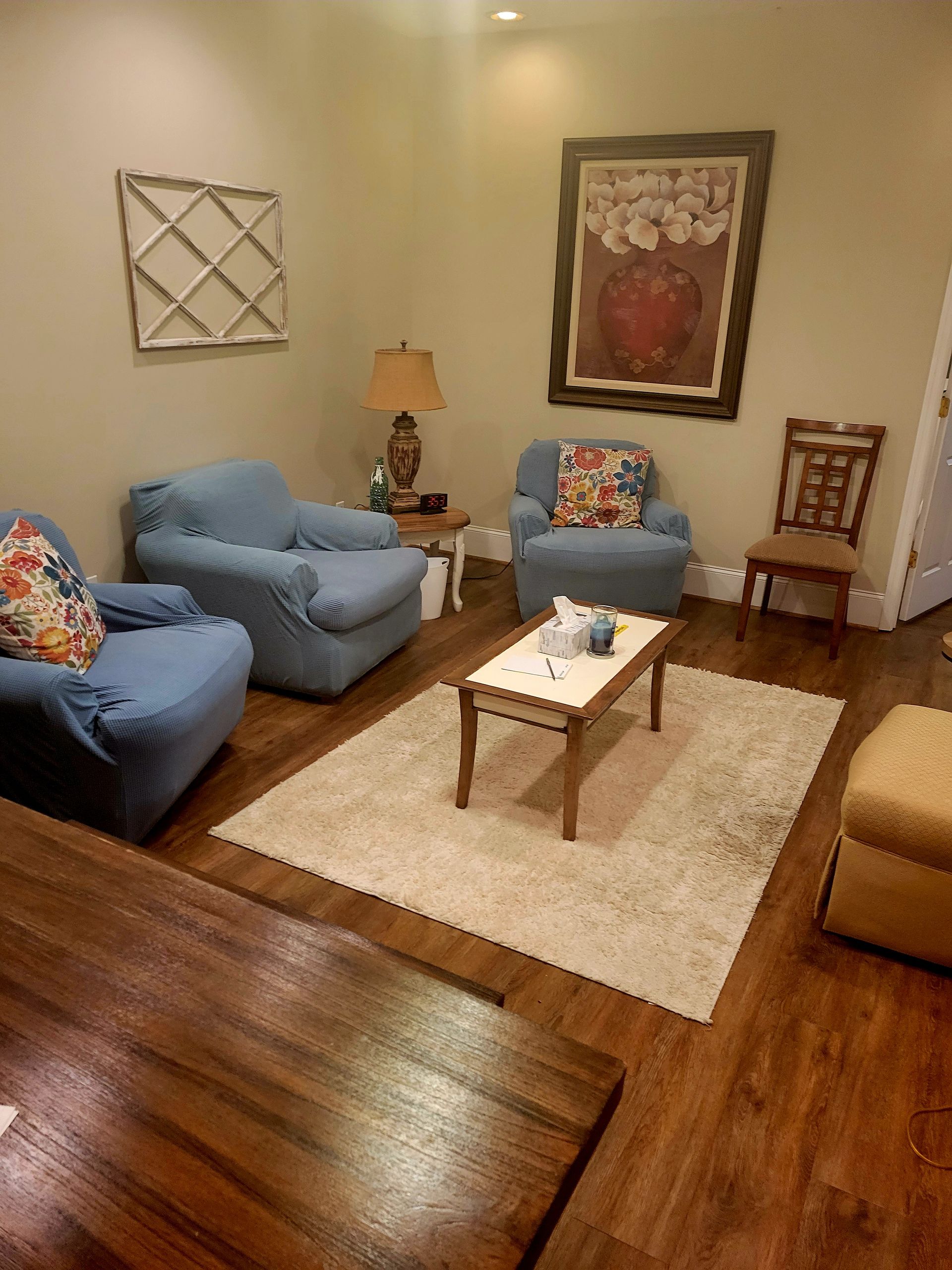 A living room with two blue chairs , a coffee table , and a rug.