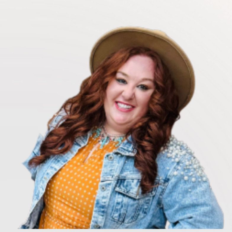 A woman with red hair is smiling and wearing a blue shirt