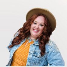 A woman with red hair is smiling and wearing a blue shirt