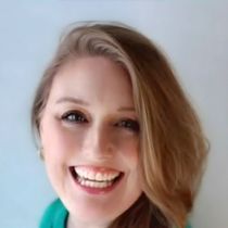 A woman with long hair is smiling and wearing a green shirt.