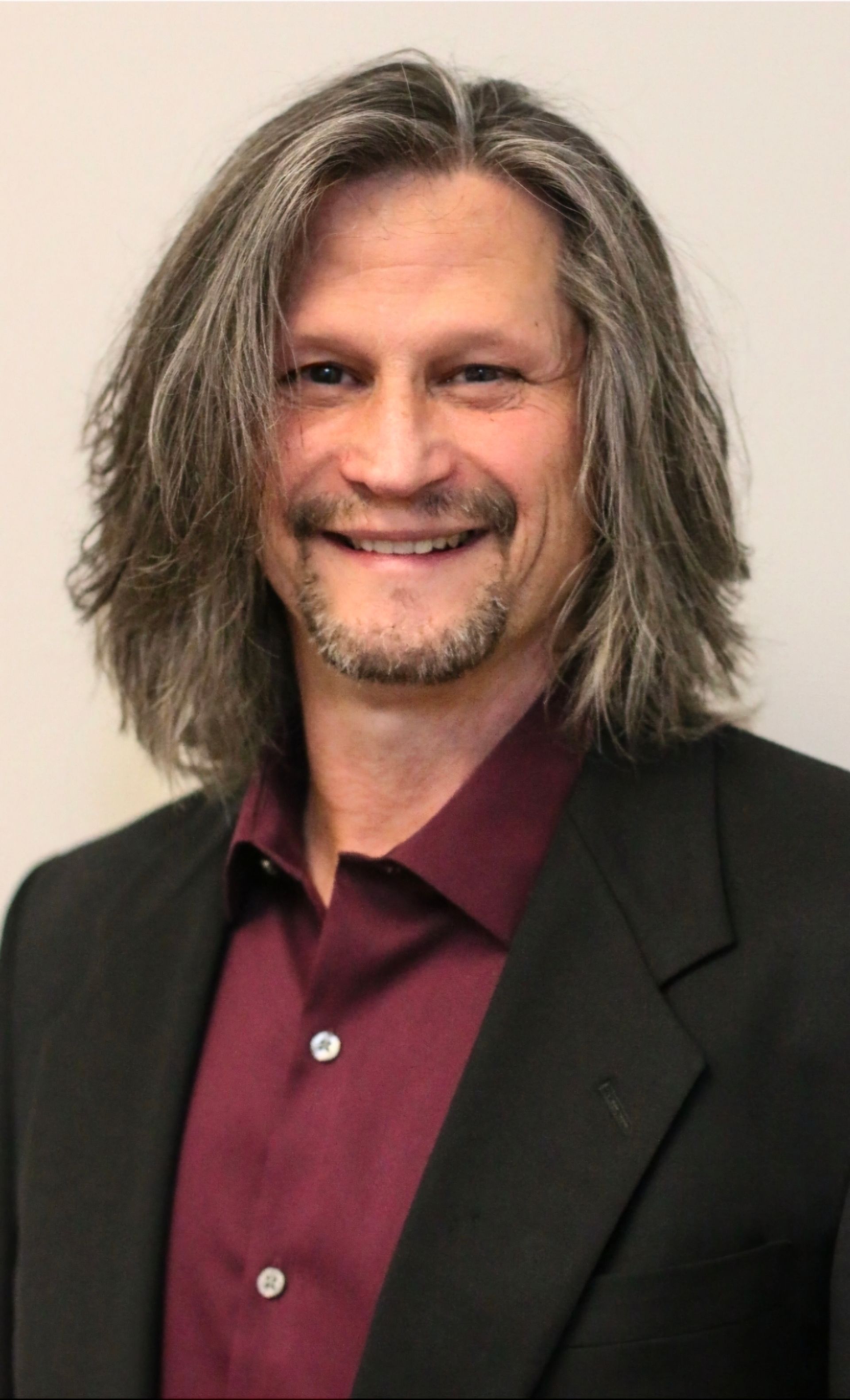 A woman with long dark hair is smiling for the camera