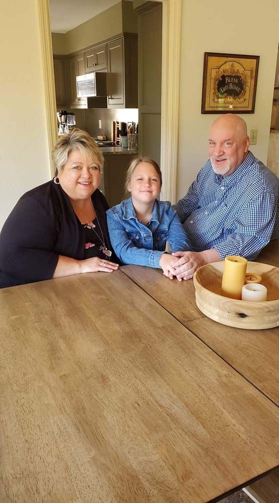 A woman , a man and a girl are sitting at a table.