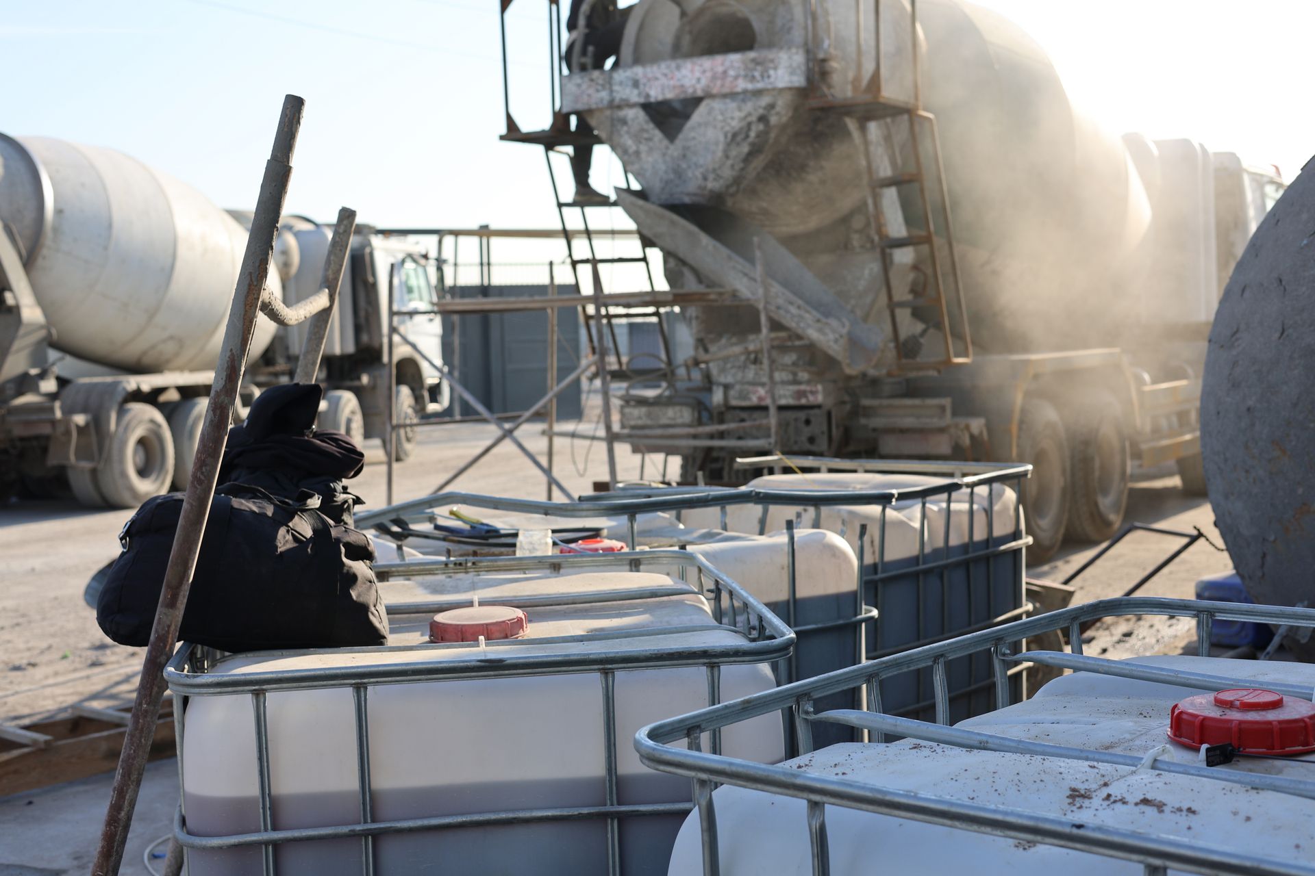 Concrete trucks at a construction site, pouring cement. White tanks in foreground