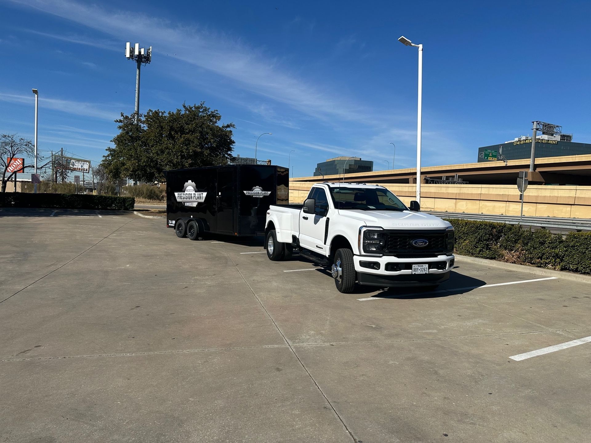 White truck towing a black enclosed trailer in a parking lot on a sunny day