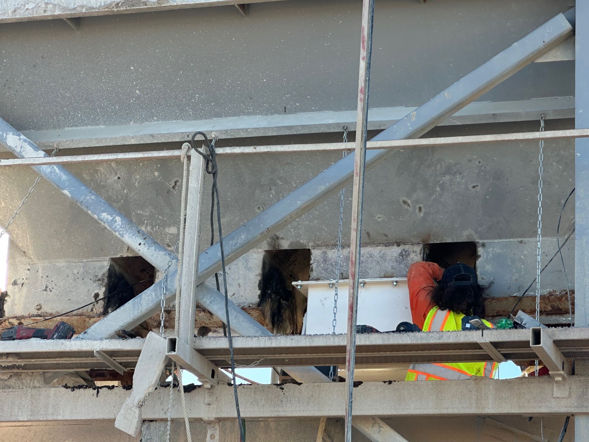 Worker in safety vest at construction site, inside metal structure, working near dark openings