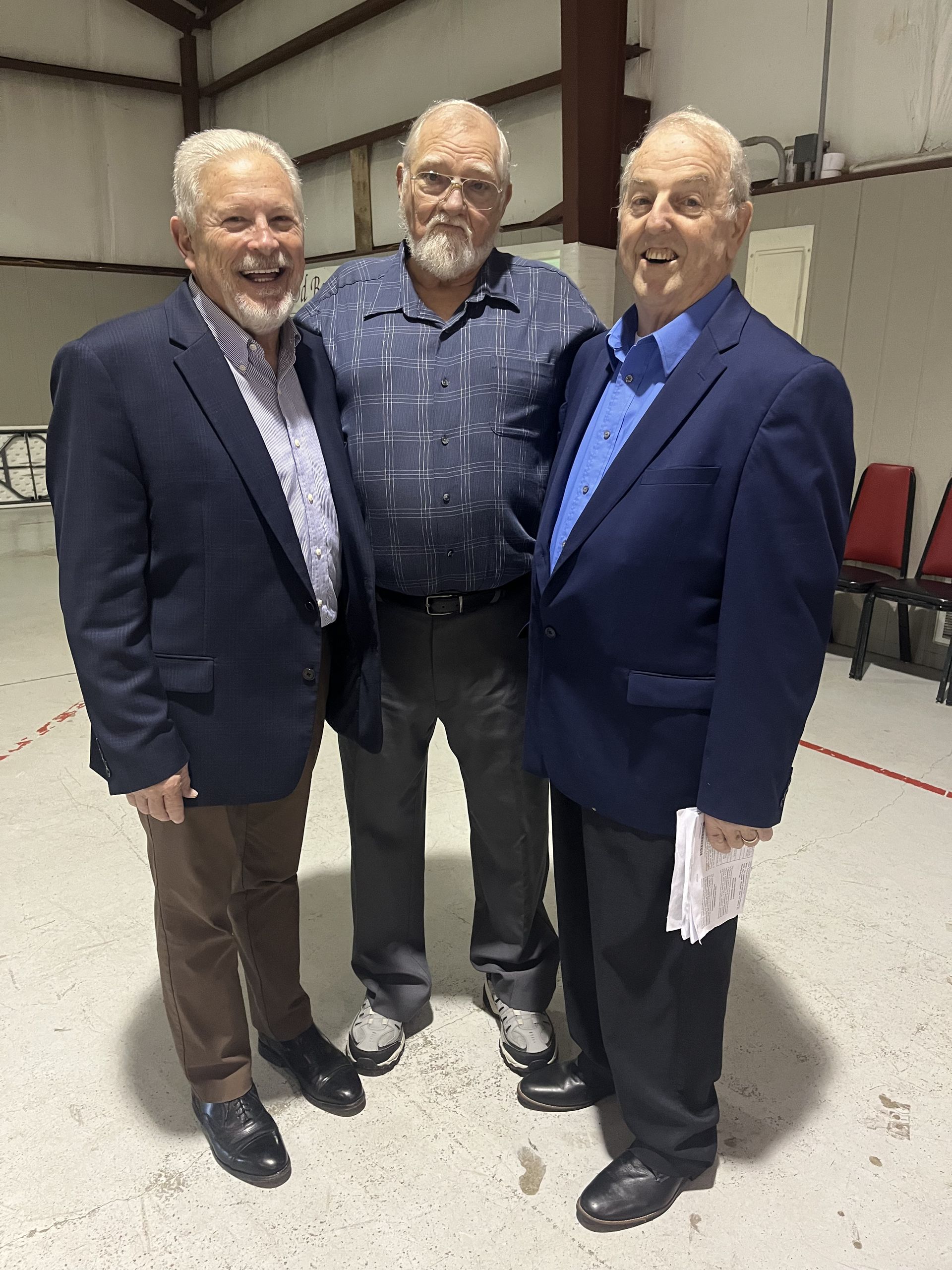 Three men in suits are standing next to each other in a room.