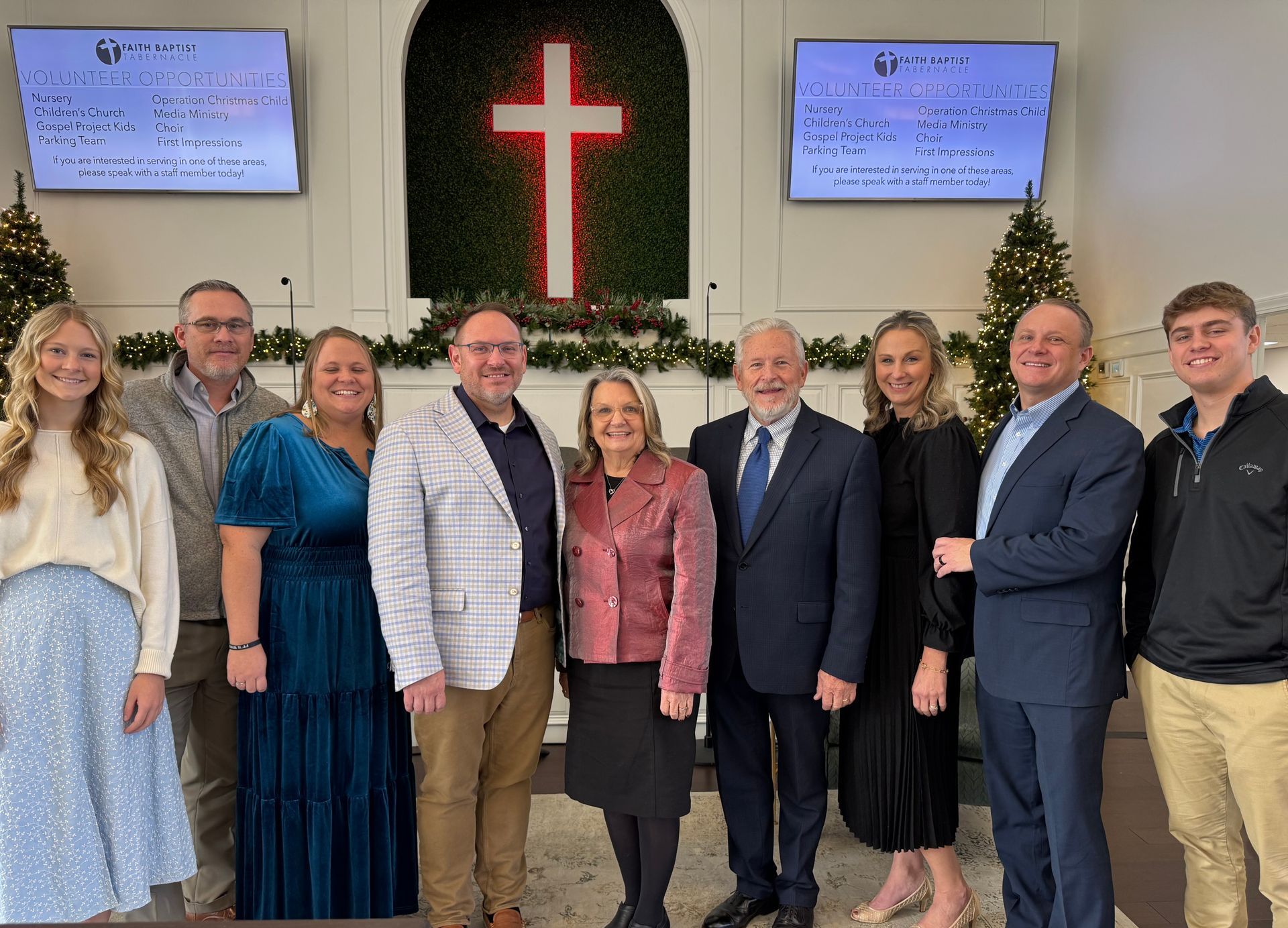 A group of people are posing for a picture in front of a cross in a church.