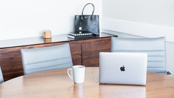 an apple laptop sits on a table next to a cup of coffee