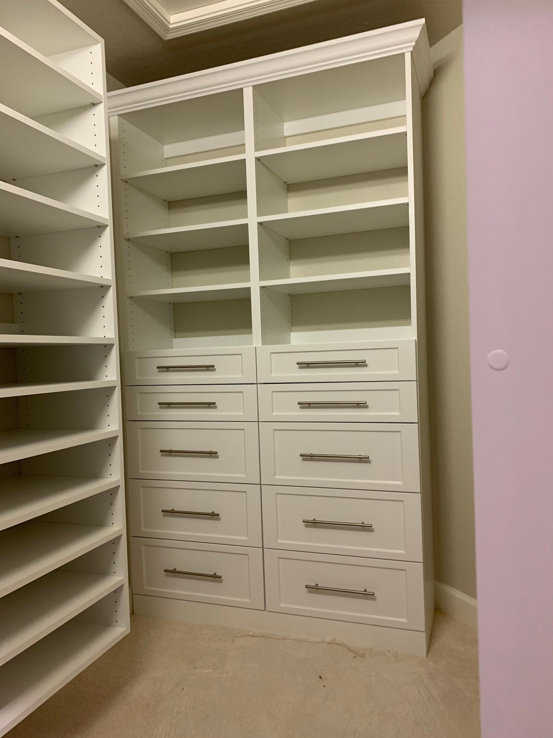 A walk in closet with lots of shelves and drawers