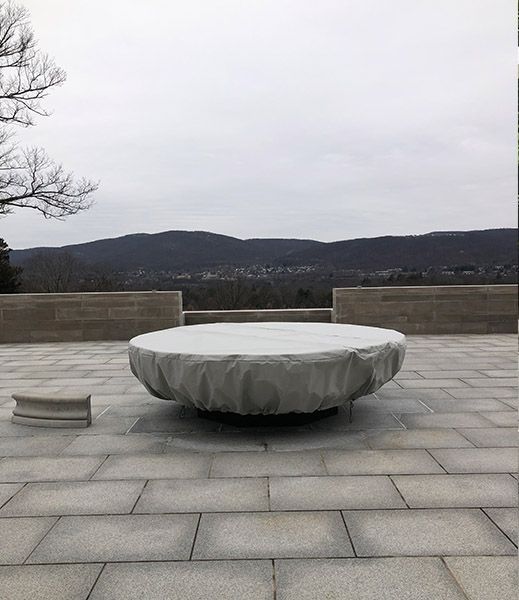 Large, covered outdoor table on a paved patio, with a view of mountains and a cloudy sky.