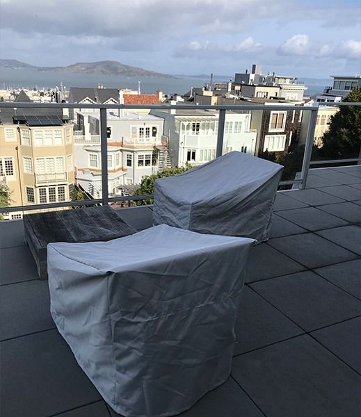 Rooftop patio with covered chairs overlooking a city and mountain in the background.
