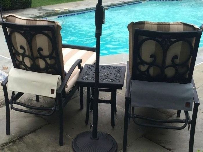 Two patio chairs with patterned cushions sit near a small table and a pool. An umbrella is positioned in the center.
