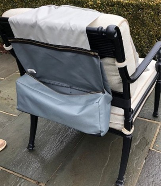 Gray chair organizer attached to the back of a black and white outdoor chair. The organizer has a zippered pocket.