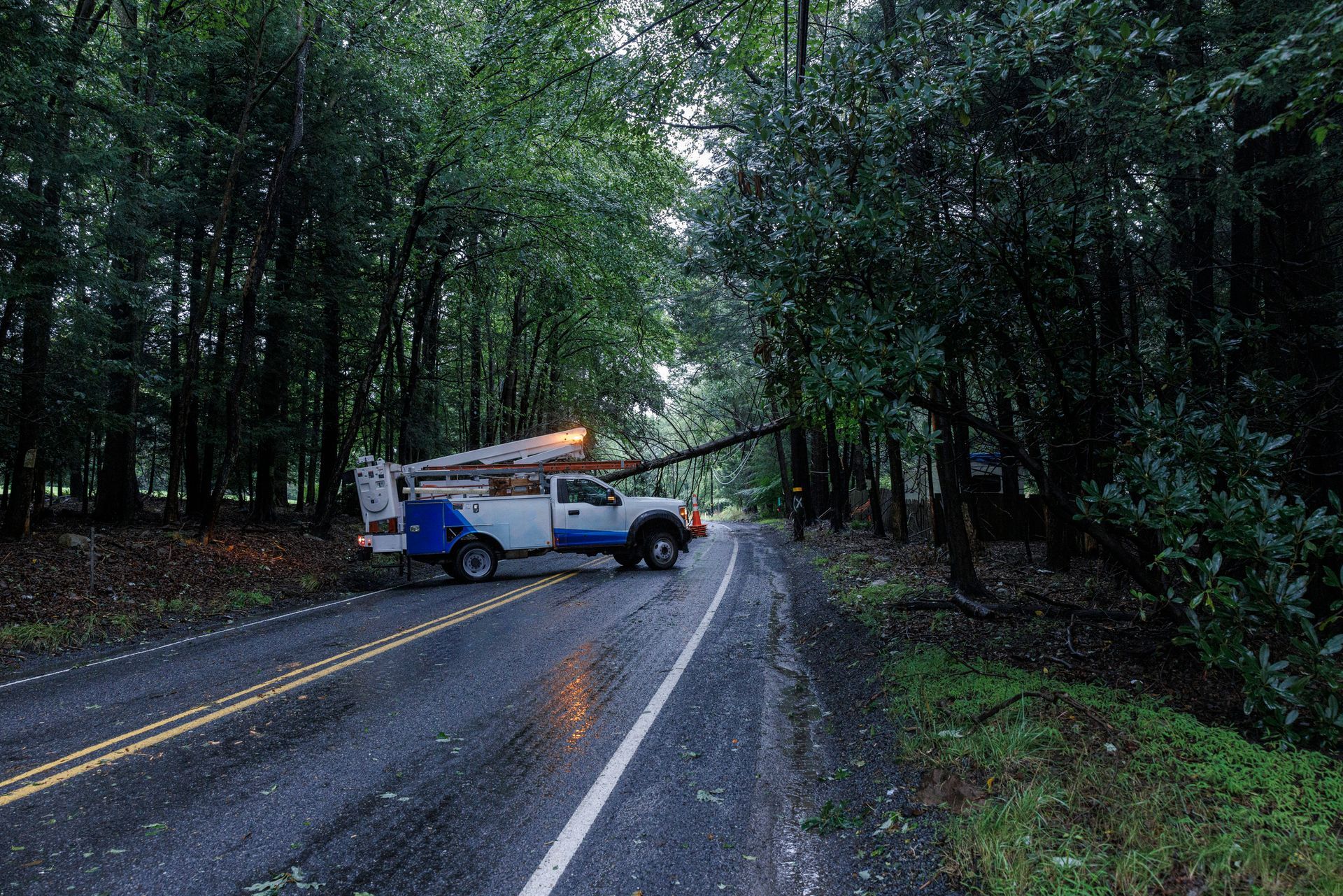 A utility truck blocking a road after a tree branch fell.