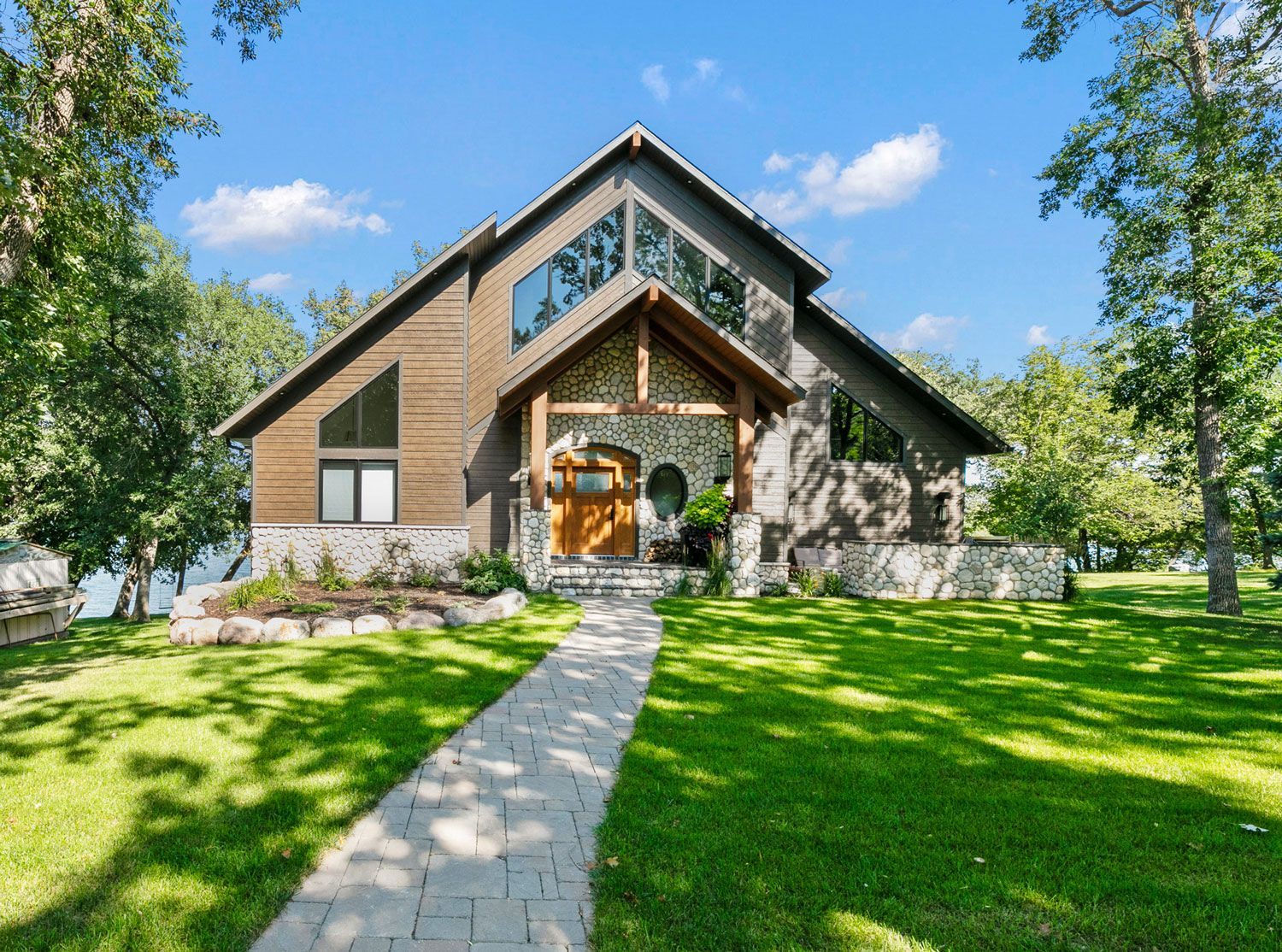 A large house with a walkway leading to it is surrounded by trees and grass.
