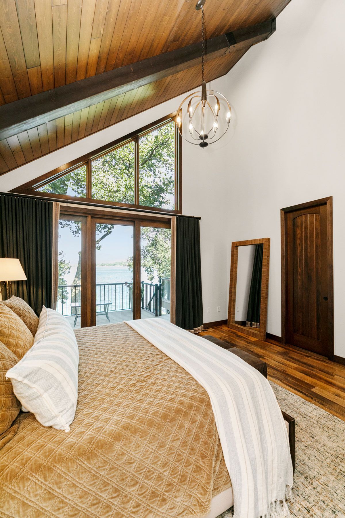 A bedroom with a large bed , a mirror , and a balcony.