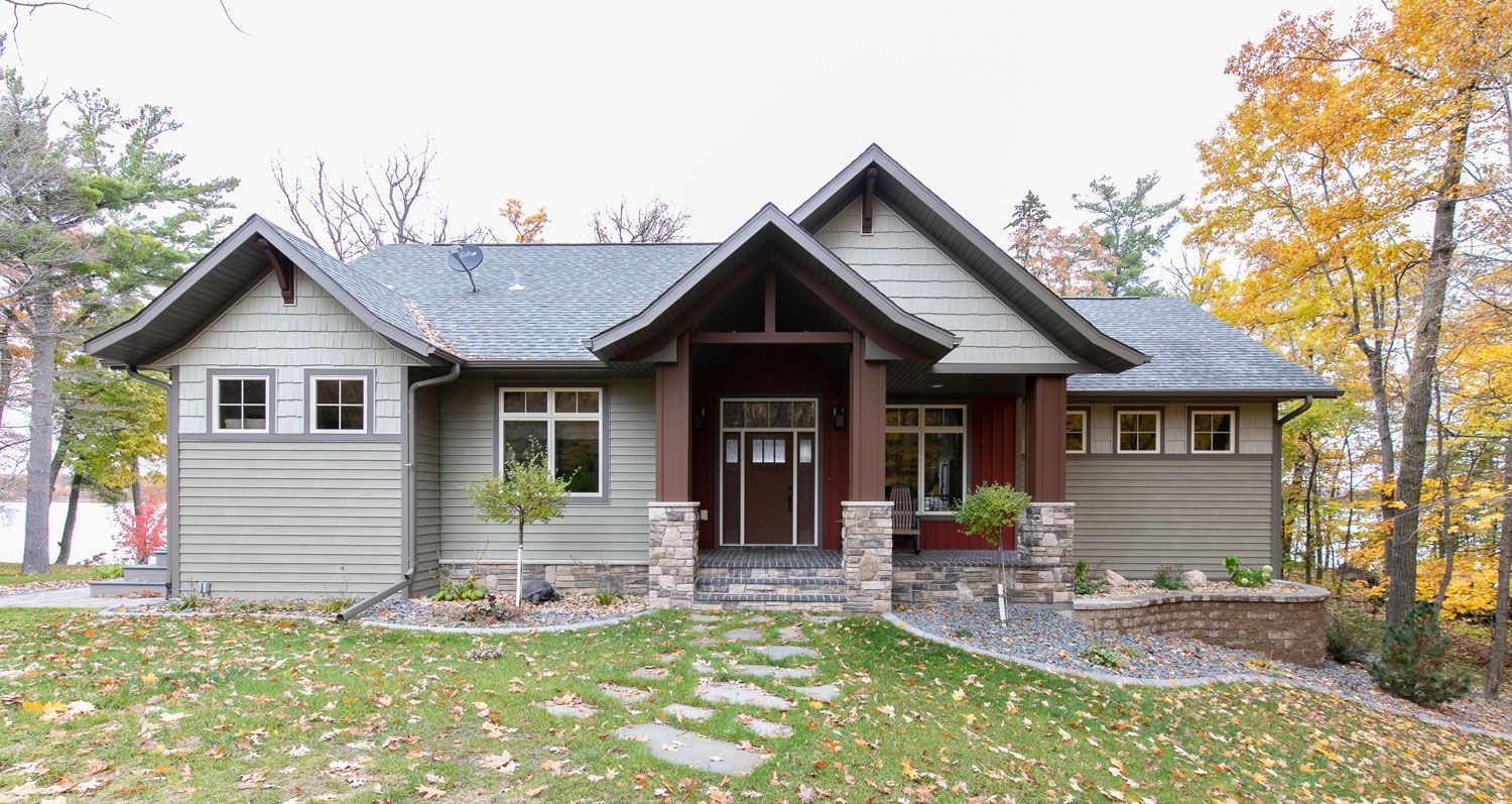 A large house is sitting on top of a lush green hill surrounded by trees.